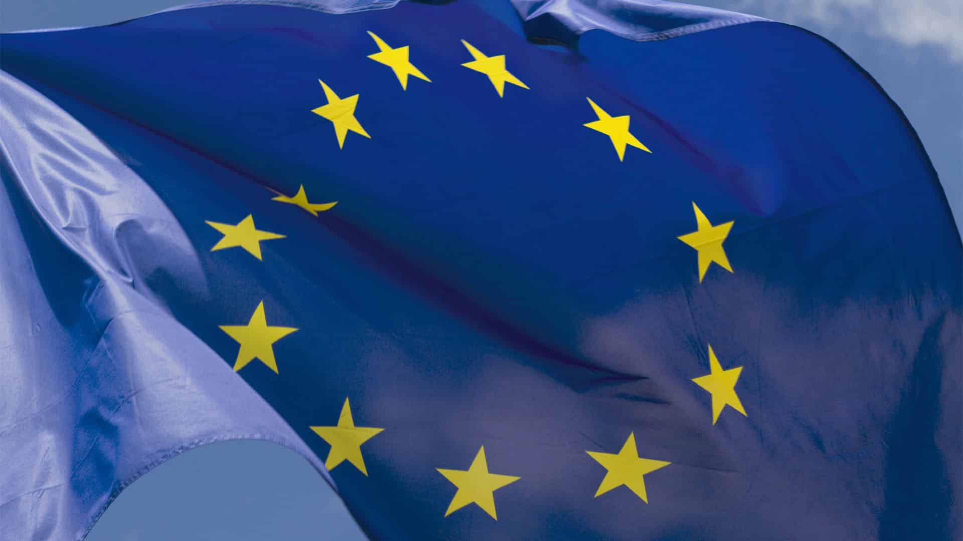 La bandera de la Unión Europea ondea en primer plano (27/06/2018) sobre un cielo claro y despejado.