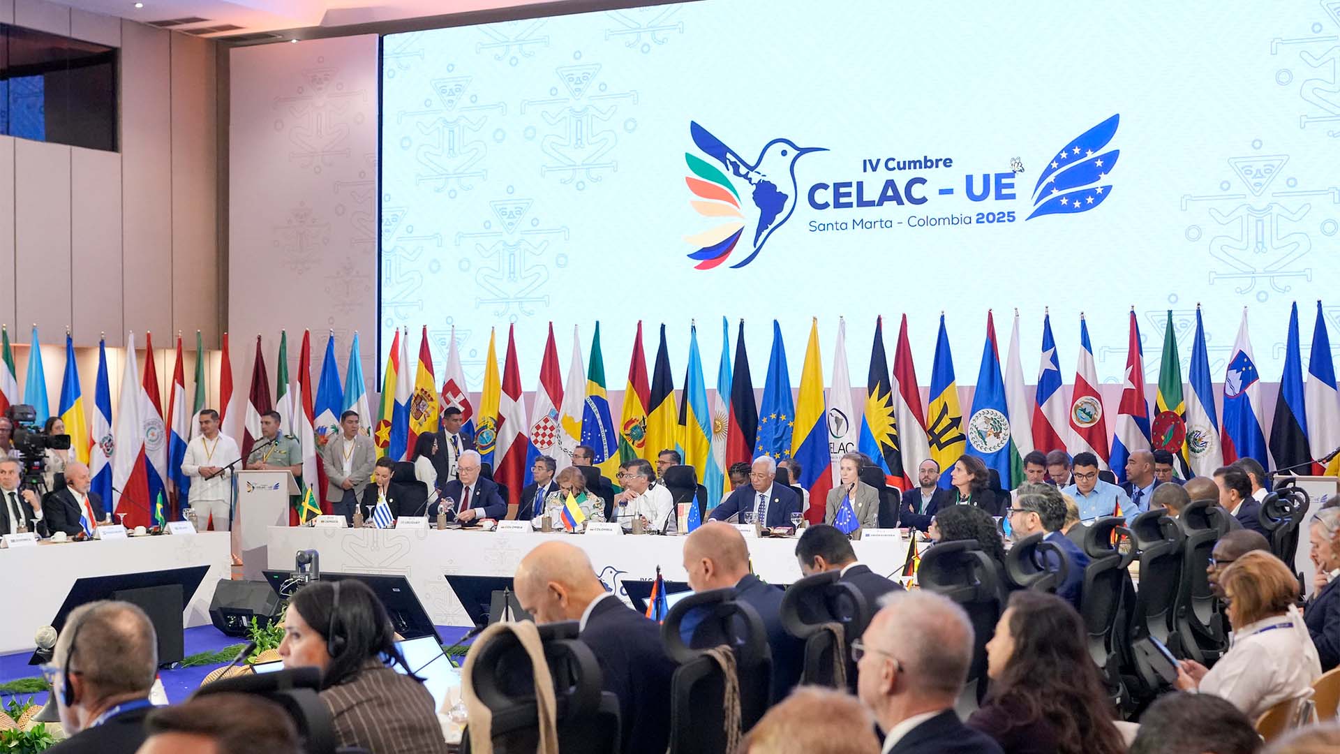 The Plenary Session of the IV EU-CELAC Summit 2025 in Santa Marta, Colombia. (09/11/2025). In the foreground, a round table with representatives from EU-CELAC member countries and institutions. Behind them, the flags of the participating countries, and in the background, a large screen displaying the logo and text of the ‘IV CELAC-EU Summit. Santa Marta – Colombia 2025’.