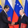 A la izquierda, Nicolás Maduro, expresidente de Venezuela, da la mano a Vladimir Putin, presidente de Rusia, en el Palacio del Kremlin, en Moscú (07/05/2025). Ambos portan una carpeta roja con el tratado de cooperación que acaban de firmar. Al fondo, varias banderas de Rusia y Venezuela.
