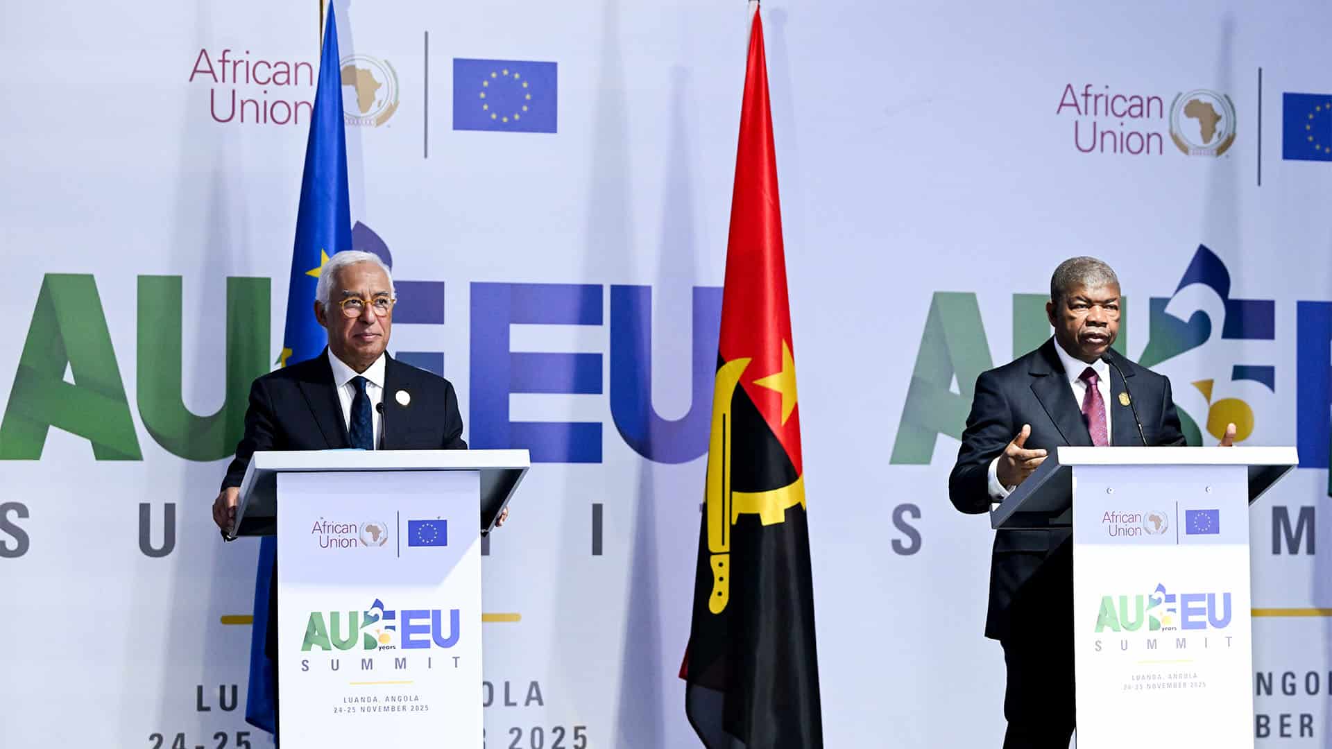 A la izquierda, el presidente del Consejo Europeo, António Costa, y, a la derecha, el presidente de la Unión Africana, João Lourenço, tras sus atriles durante la rueda de prensa de la 7ª Cumbre UA-UE (25/11/2025). Los atriles, decorados con los logos de la Unión Africana, la UE y el logo de la cumbre AU-EU. Detrás de ellos, las banderas de la UE y la Unión Africana, y, al fondo los logos de la UE y la UA, y el logo de la cumbre, y su ubicación (Luanda, Angola), así como la fecha de la cumbre (24-25 noviembre de 2025).