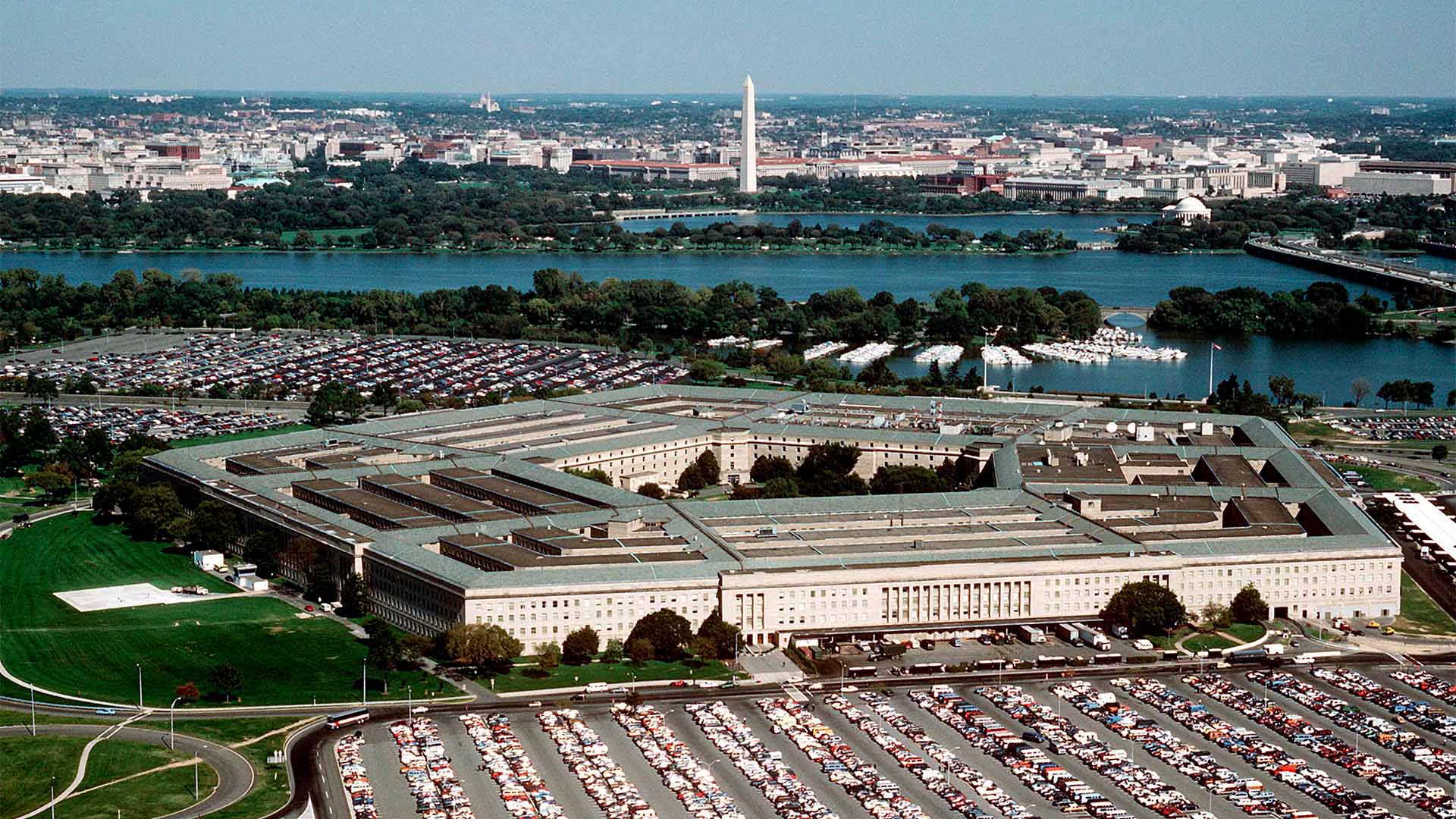 Vista aérea del Pentágono, sede del Departamento de Guerra de EEUU. Alrededor de la construcción, destacan numerosos automóviles; y, al fondo, el río Potomac y la ciudad de Washington DC.
