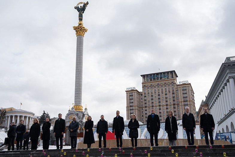 Grupo de líderes europeos reunidos en la Plaza de la Independencia en Kyiv, con motivo del cuarto aniversario de la invasión de Rusia a Ucrania. Al fondo, el capitolio con una bandera ucraniana, y detrás la columna con el monumento del Arcángel Miguel bajo el cielo nublado.