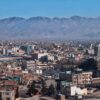 Vista general de la ciudad de Kabul, Afganistán. En primer plano, multitud de edificios residenciales y casas de baja altura, y, al fondo, difuminadas, las montañas de la ciudad delante de un cielo azul muy claro y despejado.