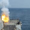 Vista parcial del buque de guerra estadounidense USS Delbert D. Black mientras lanza un misil Tomahawk, visible por el fuego que origina su salida. El buque forma parte del dispositivo de apoyo a la Operación Furia Épica (28 de febrero de 2026). El mar aparece completamente vacío y, al fondo, se ve un cielo claro y despejado.