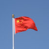 Bandera de China ondeando en un cielo azul despejado.