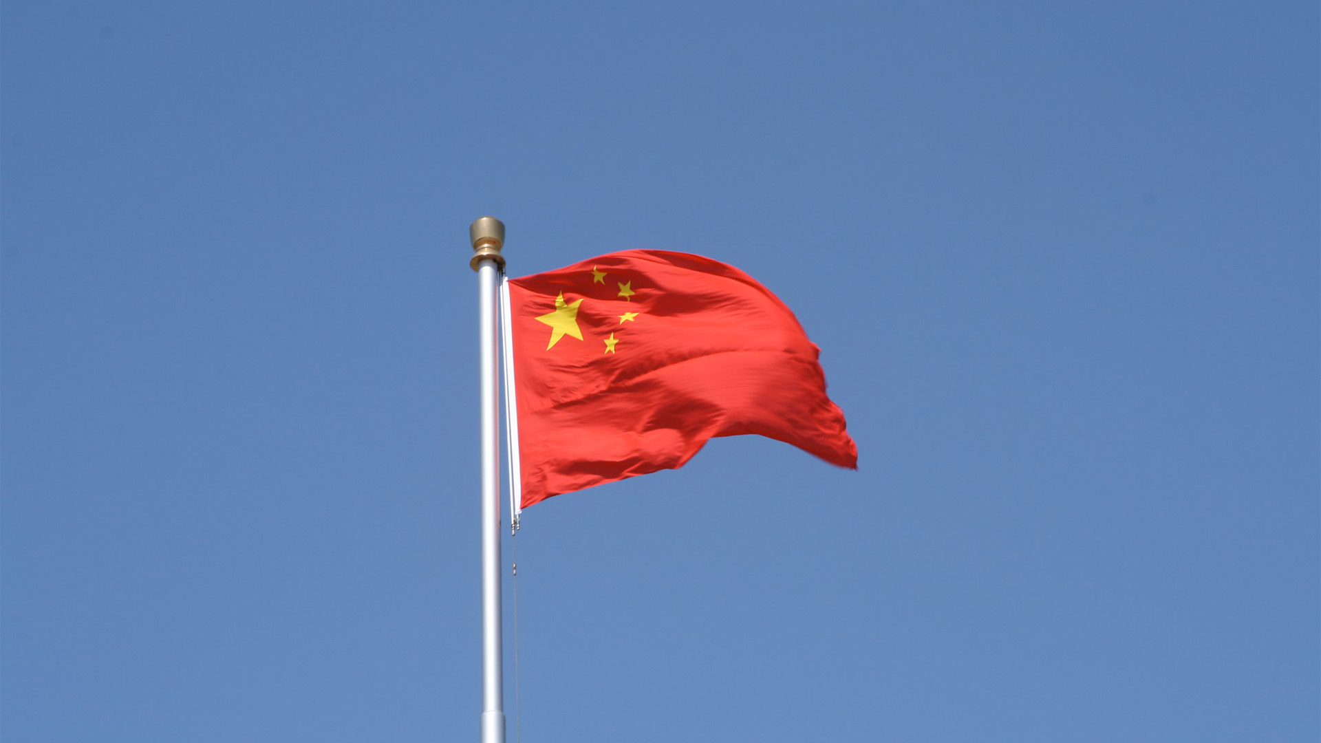 Bandera de China ondeando en un cielo azul despejado.
