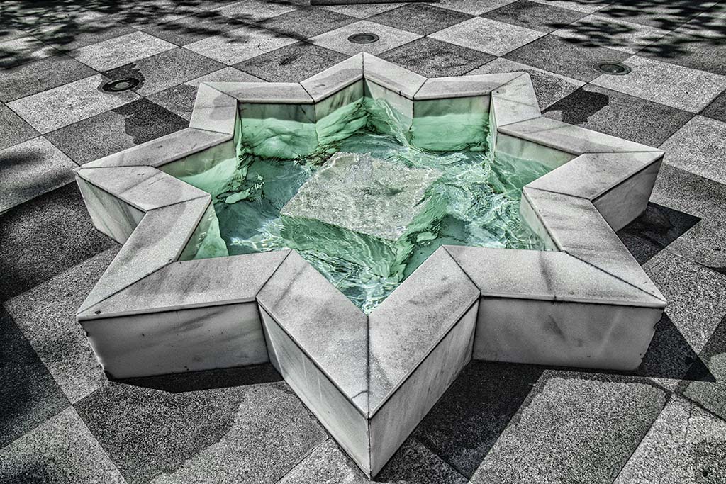 The fountain in the courtyard of the Palacio de Tejada, headquarters of the Elcano Royal Institute. This black-and-white, digitally enhanced photograph was taken from above the courtyard, where the eight-point star-shaped fountain is situated; the water in the fountain has been digitally enhanced to appear emerald. Photo: Carlos Conde. © Elcano Royal Institute.