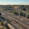Varias vías ferroviarias electrificadas del Corredor Mediterráneo atraviesan la zona de Malilla, junto a Turia Nova en Valencia, con postes, cables aéreos y vegetación en un entorno periurbano.