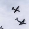 Airbus A-400M, C-130 Hércules y C-295 volando en formación durante el desfile del Ejército en el Día Nacional de España, vistos desde abajo sobre un cielo gris.