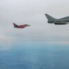 Dos aviones de combate Eurofighter Typhoon de la Fuerza Aérea alemana vuelan en formación junto a un bombardero B-52H Stratofortress de la Fuerza Aérea de Estados Unidos durante una misión en Europa. Los aviones sobrevuelan un cielo nublado y, debajo, se distinguen extensas áreas de terreno.