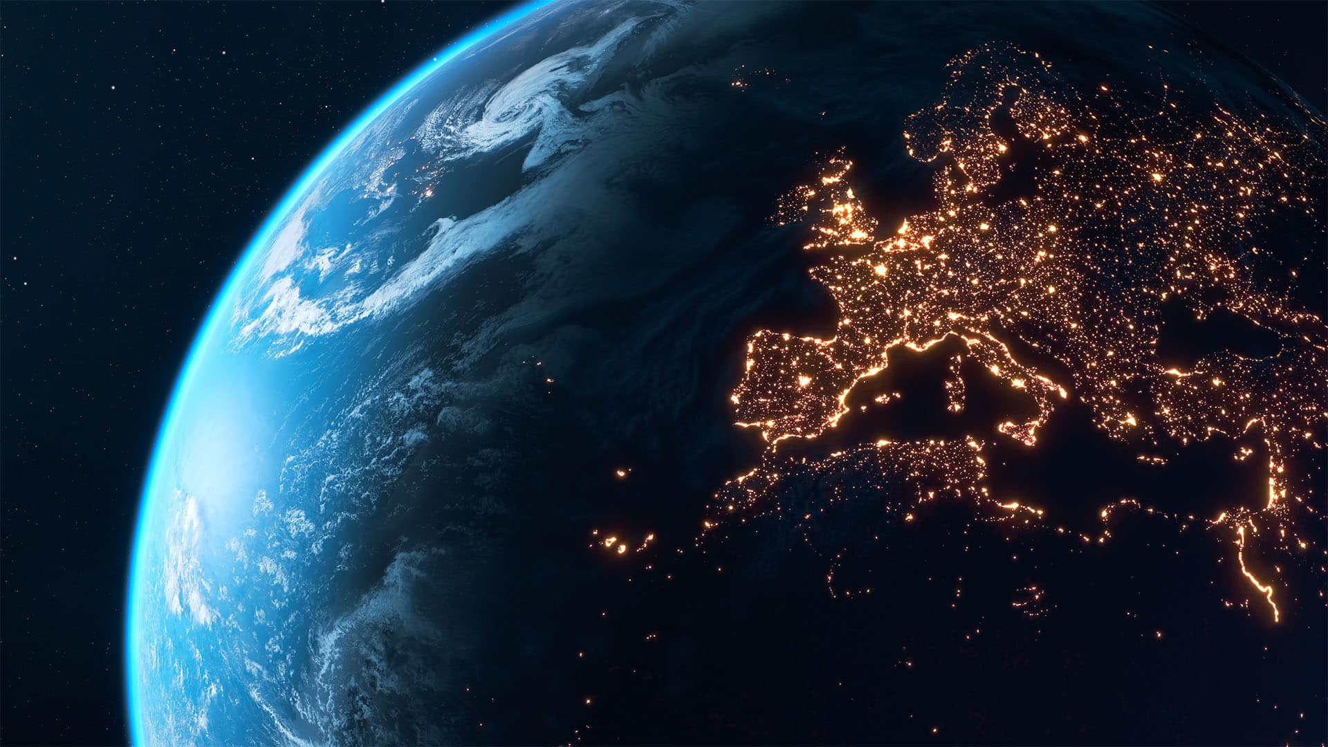 A view of the Earth from space at night, with Europe illuminated by city lights. The Iberian Peninsula, France, Italy and Central Europe are clearly visible, whilst the rest of the planet appears partially in shadow, with clouds visible over the ocean.