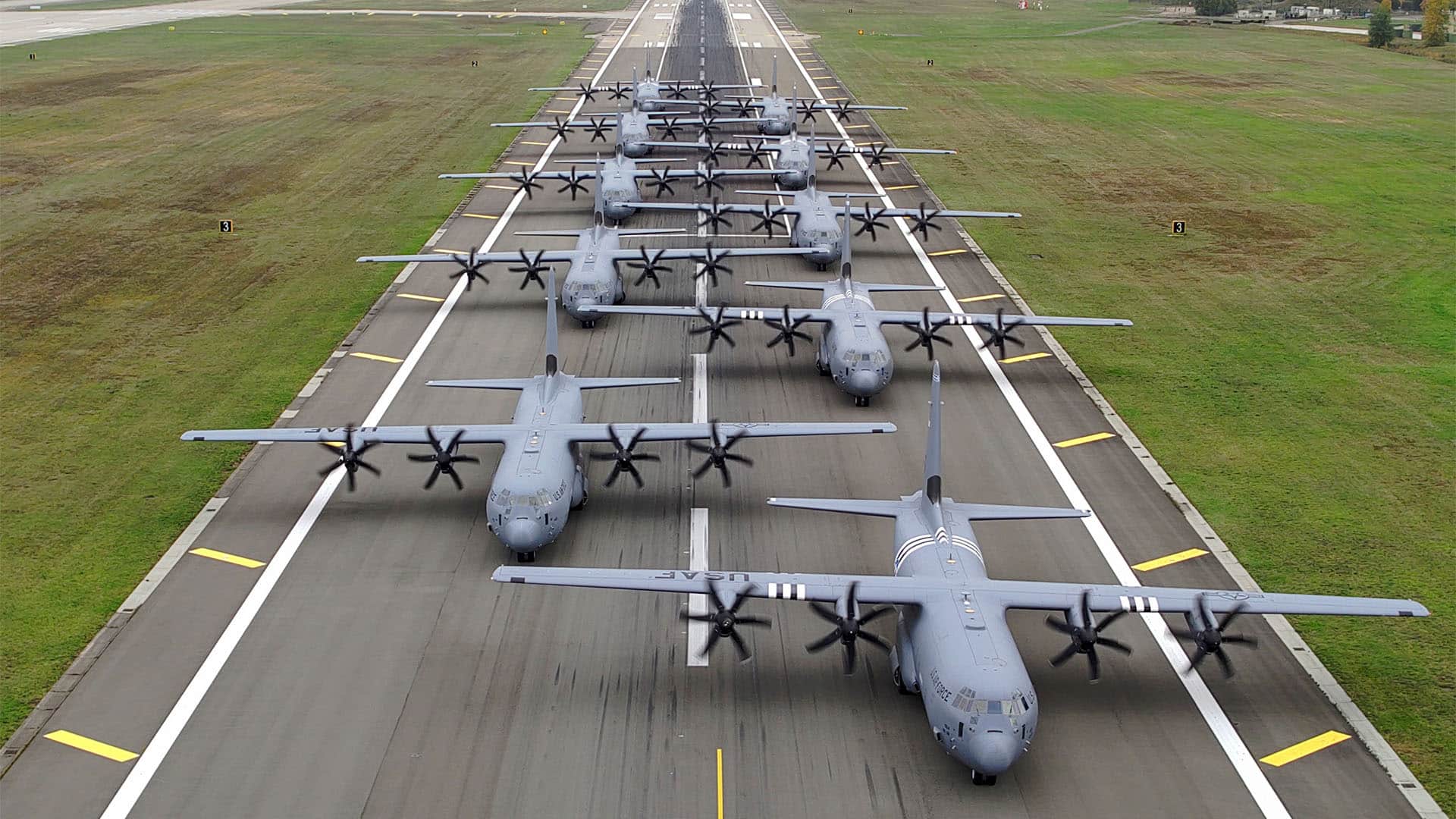 Varios aviones C-130J Super Hercules de la Fuerza Aérea de Estados Unidos regresan y se alinean sobre la pista de la base aérea de Ramstein, en Alemania. Las aeronaves están en formación sobre la pista mientras avanzan en paralelo, rodeadas de amplias zonas verdes a ambos lados de la pista de la base.