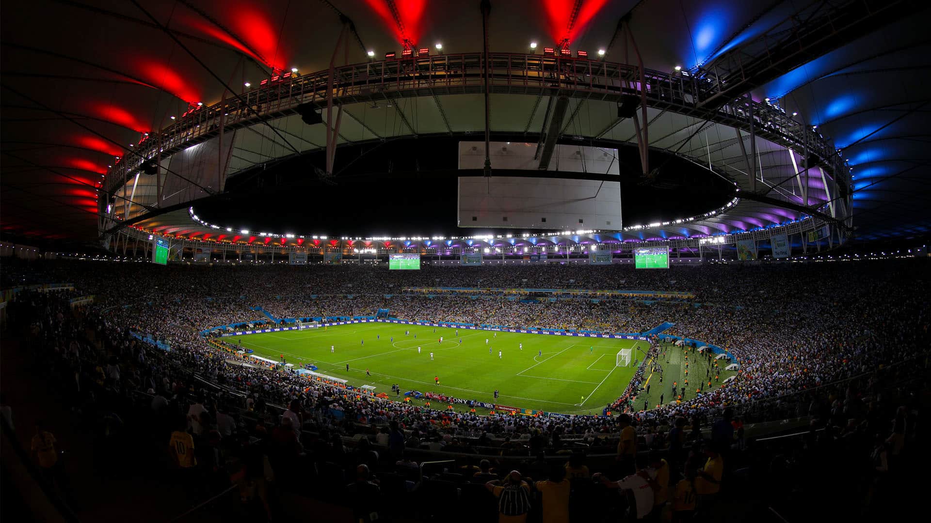 Vista panorámica del estadio Maracaná durante la final de la Copa Mundial de la FIFA 2014 entre Alemania y Argentina, celebrada el 13 de julio de 2014 en Río de Janeiro, Brasil. El estadio está lleno de aficionados y el campo iluminado se observa desde las gradas, mientras el techo del recinto destaca con luces rojas y azules sobre la multitud.
