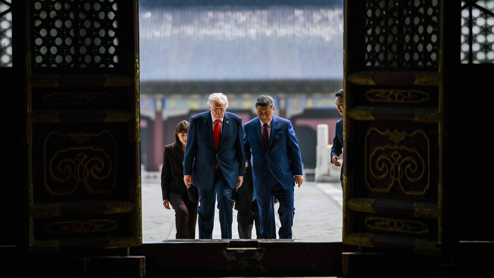 Donald Trump y Xi Jinping suben juntos unos escalones y atraviesan una gran puerta tradicional china durante una visita oficial al Templo del Cielo, en Pekín. Ambos aparecen rodeados de asistentes y enmarcados por la arquitectura oscura del edificio.