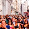 Gran Vía de Madrid llena de peatones junto a tiendas, cafeterías y edificios históricos en una concurrida tarde en el centro de la ciudad.