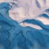 Vista aérea de un paisaje desértico en Utah donde la erosión ha modelado formas orgánicas y sinuosas. Las sombras azuladas recorren vaguadas y crestas claras, creando patrones abstractos.