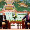 El presidente de Rusia, Vladímir Putin, y el presidente de China, Xi Jinping, mantienen una reunión oficial sentados frente a frente en un salón de Pekín. Entre ambos hay una mesa con un arreglo floral y servicio de té, mientras al fondo se observa una gran representación panorámica de la Ciudad Prohibida.