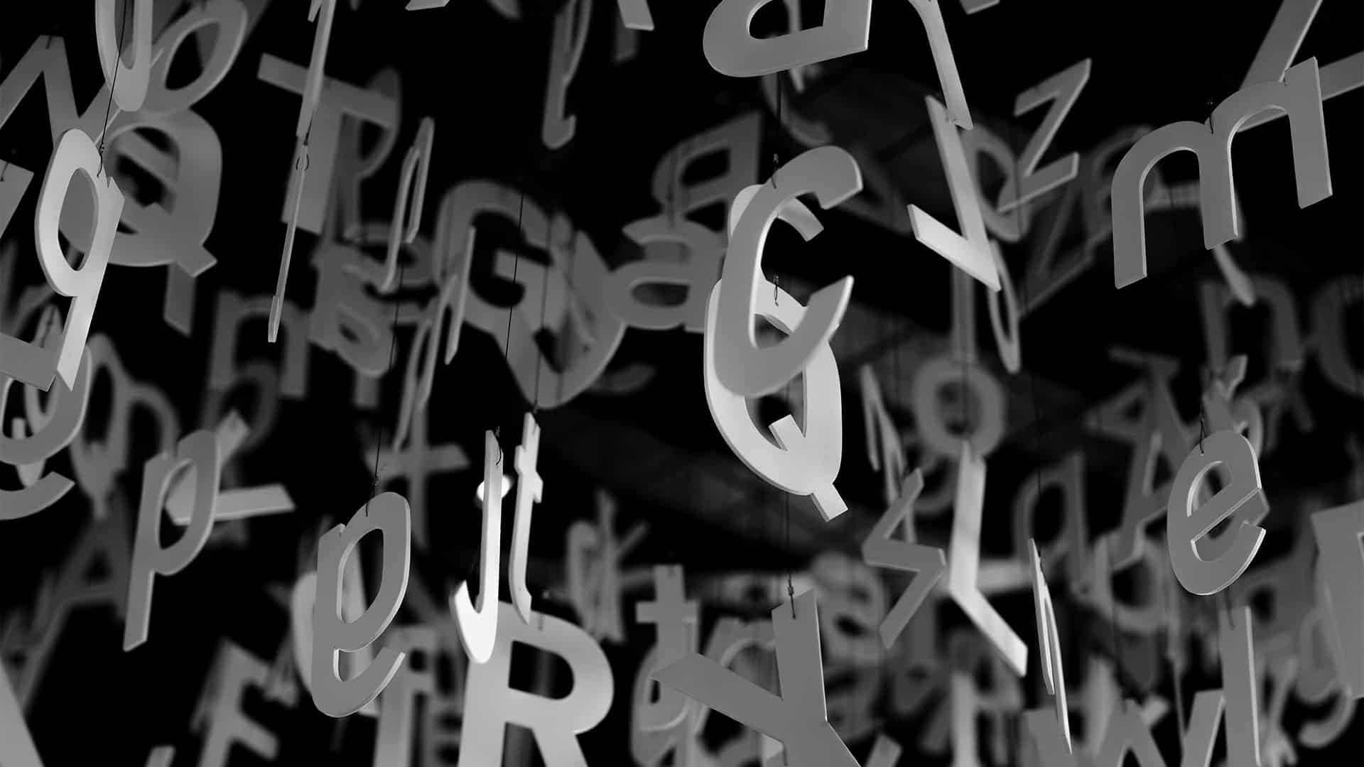 Composición de numerosas letras del alfabeto suspendidas en el aire sobre un fondo negro. Los caracteres, en tonos grises y blancos, aparecen distribuidos de forma caótica y a distintas profundidades.
