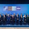 Fotografía de grupo de la cumbre de la OTAN en Ankara. Varias decenas de líderes y representantes posan de pie en tres filas sobre una tarima azul, con un fondo institucional en tonos azules y el cartel “NATO OTAN Ankara Summit 7-8 VII 2026” en la parte superior.