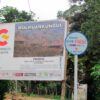Cartel de la Cooperación Española sobre un proyecto de agua y saneamiento en comunidades de la Sierra Nevada de Santa Marta, Colombia rodeado de vegetación.