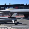 Exposición al aire libre de la maqueta a escala 1 del proyecto de avión de combate FCAS NGF (Next Generation Fighter) junto con los efectores externos expuestas en el stand de Dassault Aviation en el Salón Aeronáutico de Le Bourget 2019. Detrás de las barreras de seguridad, numerosos visitantes observan la muestra durante un evento del sector aeroespacial y de defensa bajo un cielo despejado.
