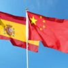 Banderas de España y de la República Popular China en sus respectivos mástiles ondeando en el cielo.