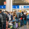 Numerosos viajeros con maletas y mochilas esperan en una larga fila ante los controles de pasaportes del aeropuerto de Milán-Malpensa, con carteles que indican el acceso para todos los pasaportes y viajeros extracomunitarios.
