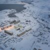 Aerial view of Teriberka in the Russian Arctic, with buildings along the coast surrounded by an extensive snow-covered landscape.