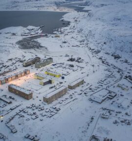 Vista aérea de Teriberka, en el Ártico ruso, con edificios junto a la costa rodeados por un extenso paisaje cubierto de nieve.