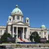Fachada de la Asamblea Nacional de Serbia, en Belgrado, con varias banderas serbias frente al edificio y su característica cúpula central.