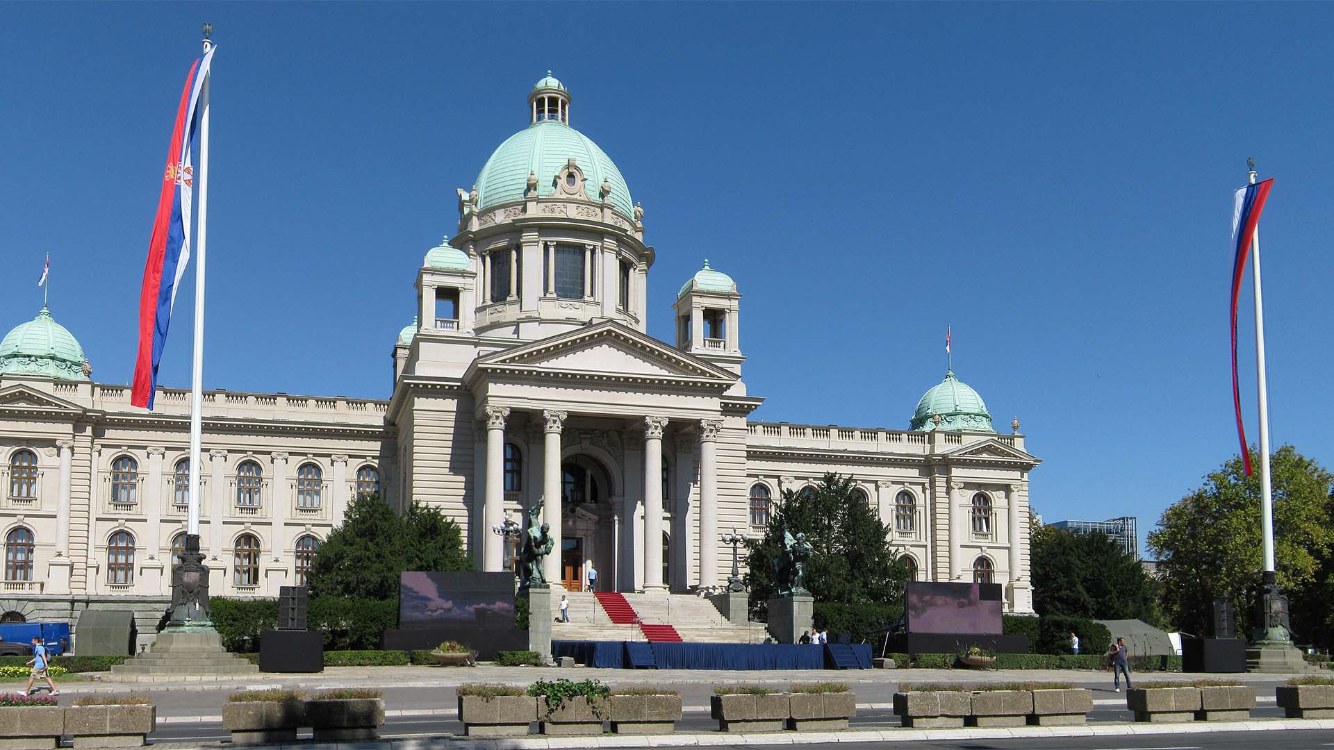 Fachada de la Asamblea Nacional de Serbia, en Belgrado, con varias banderas serbias frente al edificio y su característica cúpula central.