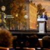 Vladímir Putin interviene desde un atril ante el público durante el XII Foro Internacional de las Culturas Unidas de San Petersburgo, con una gran pantalla de fondo con la imagen de la ciudad.