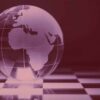 Globo terráqueo de cristal con Europa, África y parte de Asia grabadas, colocado sobre un tablero de ajedrez en tonos rojizos.