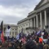 Multitud de manifestantes con banderas estadounidenses y pancartas de apoyo a Donald Trump se concentra frente al Capitolio de EEUU, mientras varias personas suben por las escalinatas del edificio durante el asalto del 6 de enero de 2021.