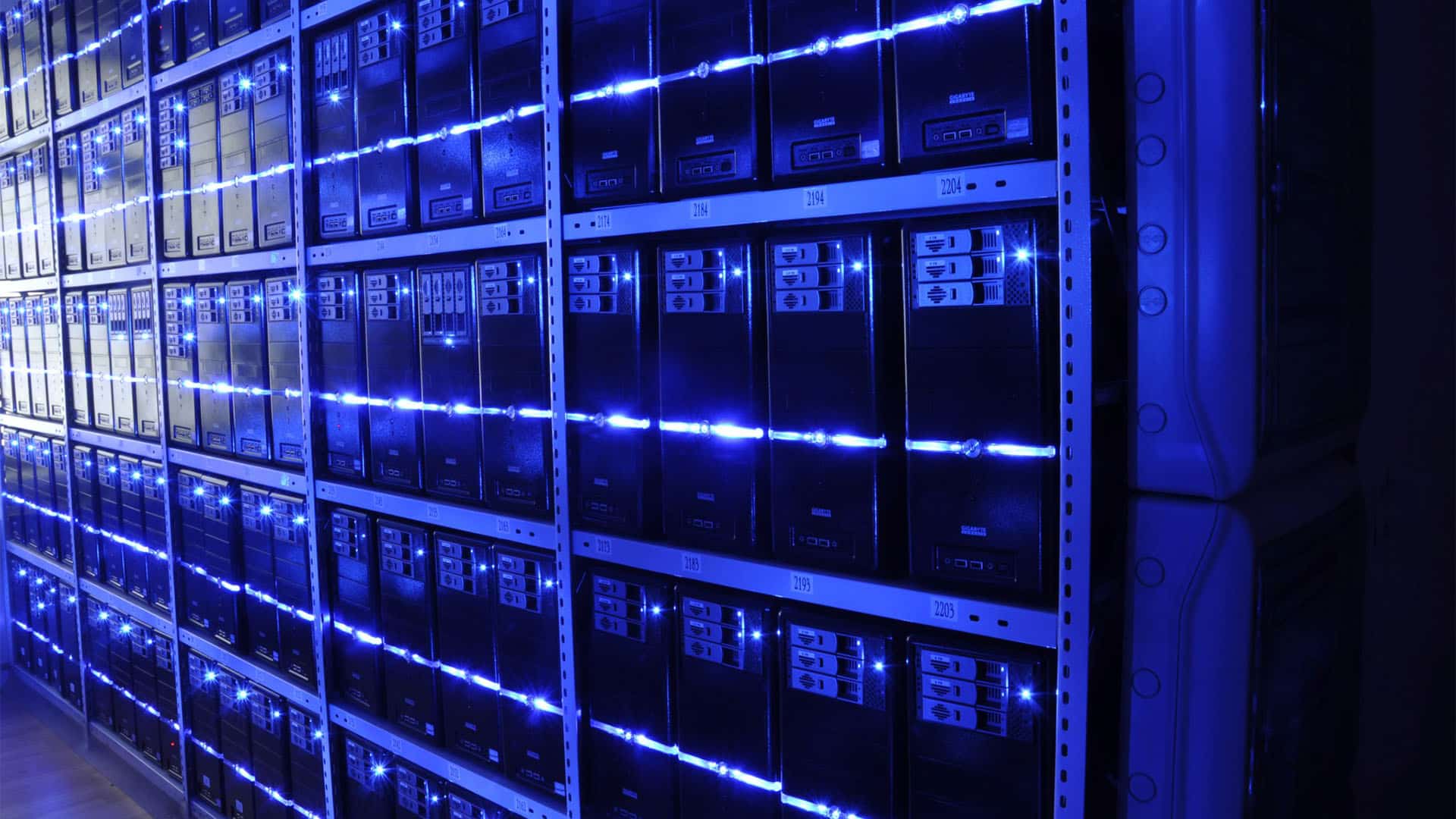 Rows of servers and computer equipment installed in metal racks and illuminated by blue lights at the BalticServers data centre, Lithuania.