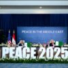 Ceremonia de firma del acuerdo de alto el fuego en la Cumbre en Sharm el-Sheikh (Egipto). En primer plano las palabras “Peace 2025”, en la mesa sentados sosteniendo las carpetas del acuerdo destacan Abdelfatah al Sisi (presidente de Egipto) y Donald Trump (presidente de EEUU). Al fondo las banderas de EEUU, Egipto, Qatar y Turquía, el resto de lideres mundiales, y una pantalla con las palabras “Peace in the Middle East”.