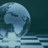Globo terráqueo de cristal con Europa, África y parte de Asia grabadas, colocado sobre un tablero de ajedrez en tonos turquesas.