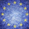 Aerial view of hundreds of people walking on a blue surface with twelve large yellow stars arranged in a circle, representing the European Union flag.
