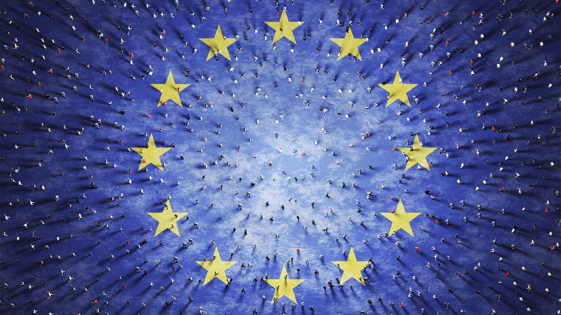 Aerial view of hundreds of people walking on a blue surface with twelve large yellow stars arranged in a circle, representing the European Union flag.