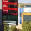 Un panel de precios en una gasolinera en Los Ángeles (EEUU) muestra los precios de la gasolina y diésel extremadamente altos. Al fondo edificios, dos farolas (una con) con semáforos y árboles en un día soleado.